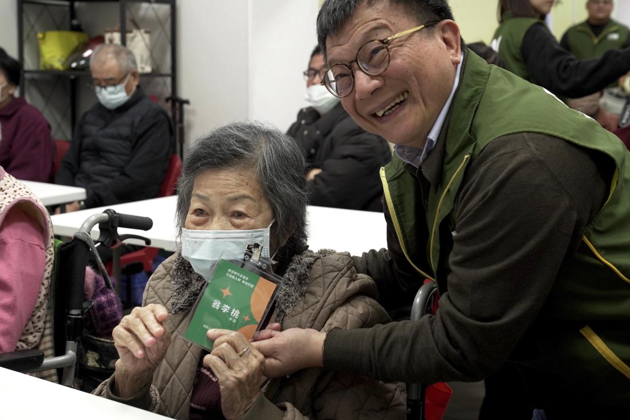 芥菜種會執行長李肇家(右一)為五股助人網「樂福學堂」長者們掛學生證,給予愛的祝福。(芥菜種會提供)