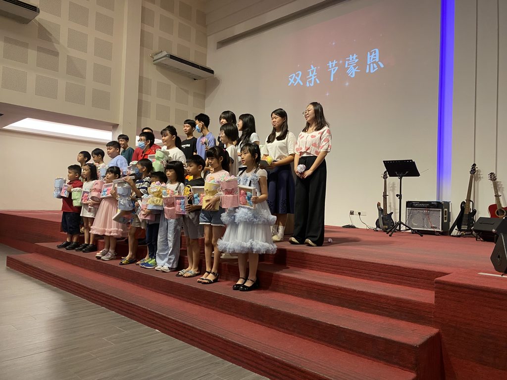 主日「雙親節蒙恩」獻禮儀式：恩惠堂的孩子與青少年並排於台前，手捧為父母預備的禮物，向長輩表達感恩